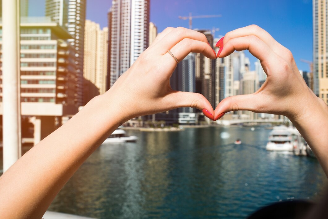 Hands forming a heart shape in front of Dubai skyscrapers, representing love for the city in a visa guide article.